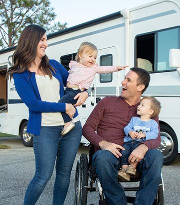 man in wheelchair with family and motorhome nearby